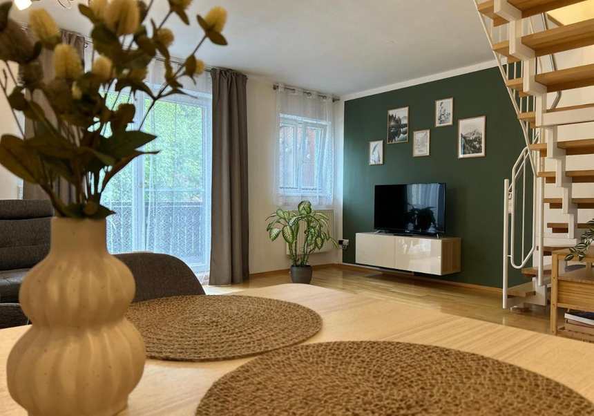 Wohnzimmer mit grüner Wand und offener Holztreppe